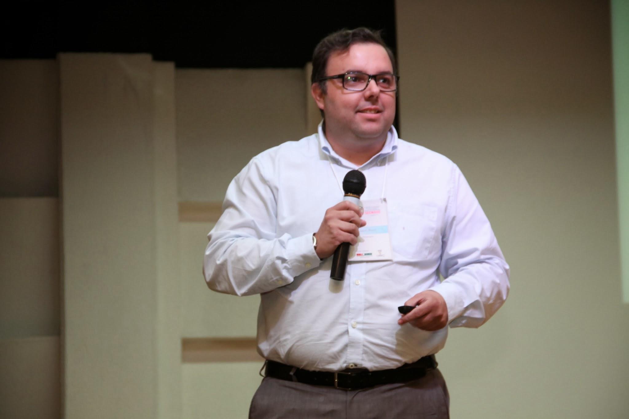 Palestrante Almir Neves no palco com microfone em evento corporativo